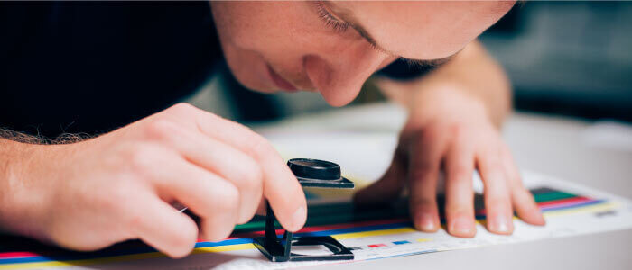 Worker in printing factory using magnifying glass
